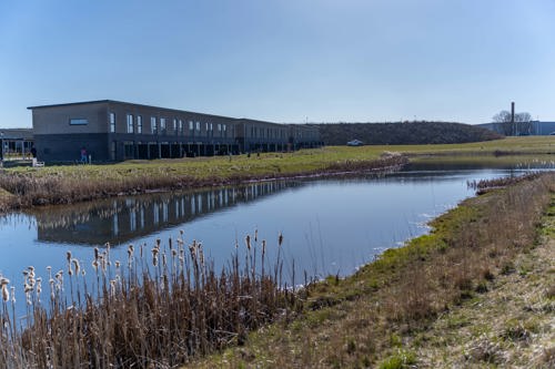 Billede af Remmerslund Skovby, med boliger i baggrunden og en sø i forgrunden.