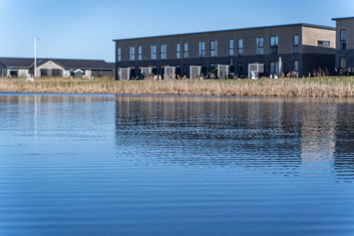 Billede af Remmerslund Skovby, med boliger i baggrunden og en sø i forgrunden.